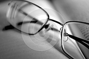 A pair of glasses on a book in black and white photo